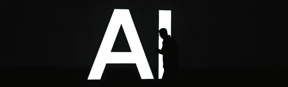 Silhouette of a person walking past large illuminated AI letters in the dark